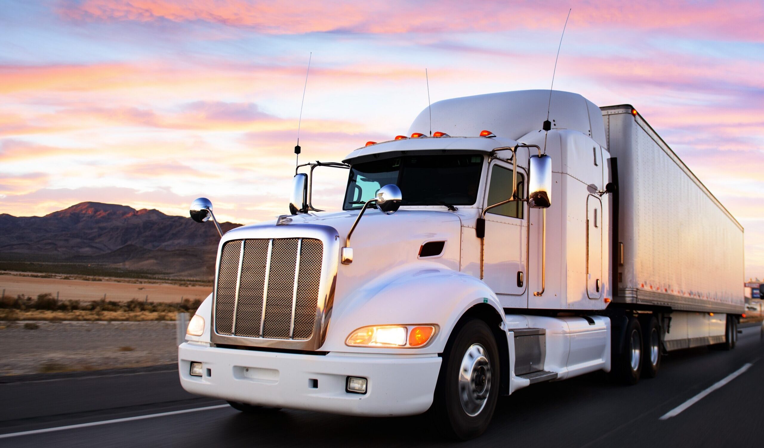A white 18-wheeler truck speeds along the highway in El Paso to deliver goods across the country. 