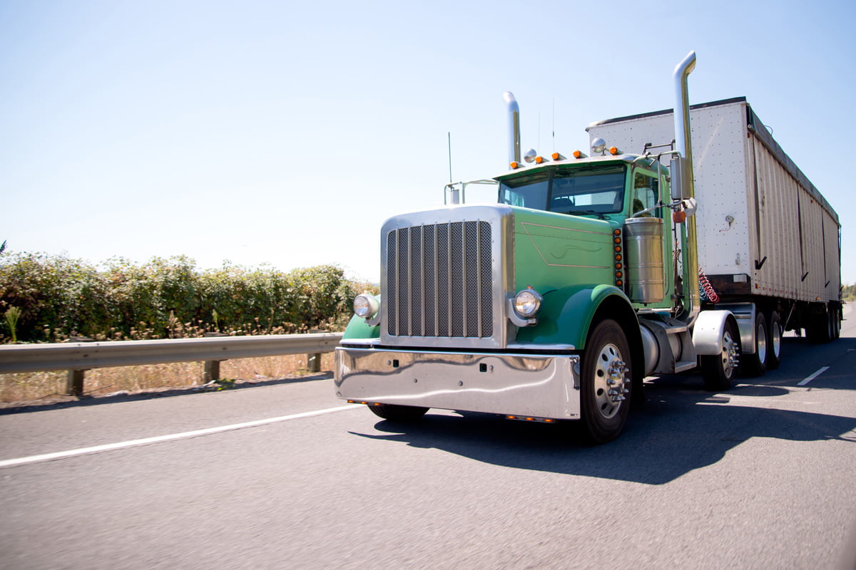 Front view of a green and white truck driving in El Paso.
