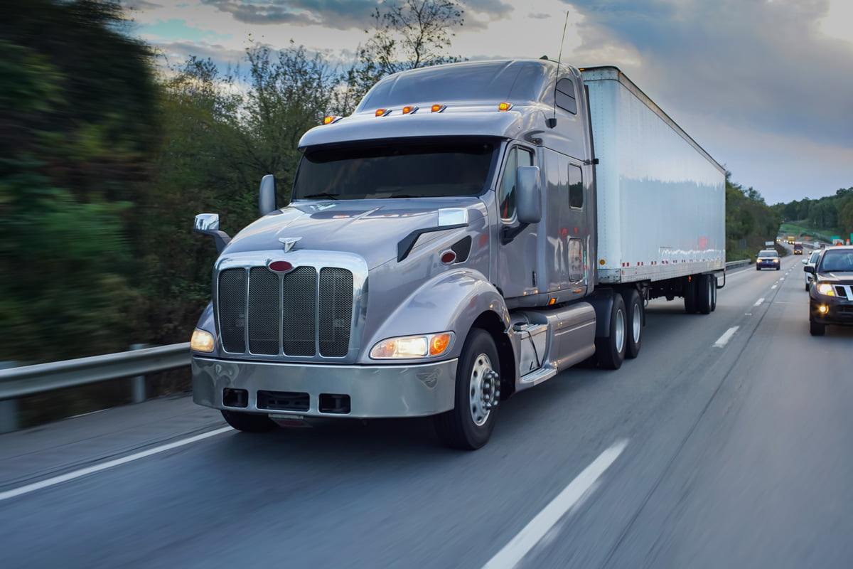 A grey and white semi-truck driving on a freeway in El Paso.
